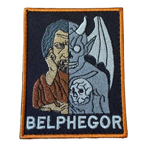 May include: A rectangular embroidered patch with an orange border on a black background. The design features a split face: a human figure on the left and a grey demon with a horn and wing on the right. The text BELPHEGOR is stitched in white at the bottom.