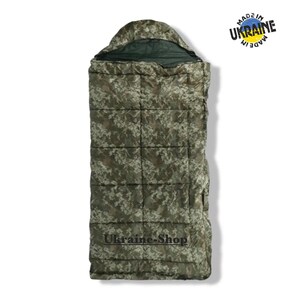 Op de afbeelding: Een rechthoekige slaapzak met een groen en bruin camouflagepatroon en een capuchon. De tekst Ukraine-Shop staat in het zwart onderaan gedrukt en rechtsboven bevindt zich een rond logo met de tekst Made in Ukraine.