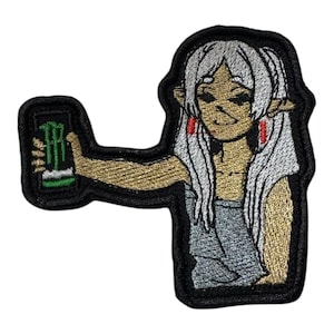 May include: Embroidered patch featuring a cartoon character with long white hair and pointed ears, holding a green and black energy drink can. The patch has a black border and is made with gold, silver, and red thread.