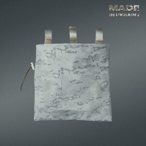 May include: A white and gray camouflage pouch with three tan straps at the top and a drawstring closure. The text "MADE IN UKRAINE" is visible in the upper right corner. The pouch is designed for carrying small items.