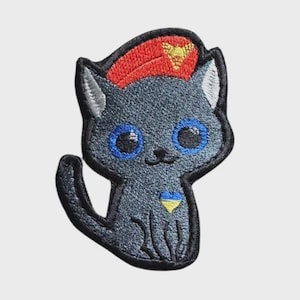 May include: Embroidered patch featuring a cartoon cat in shades of gray, with blue eyes and a red hat. The cat has a yellow and blue emblem on its chest. The patch is designed with a black border.