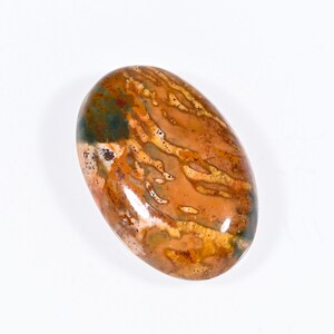 Könnte beinhalten: Ovaler Edelstein mit polierter Oberfläche. Der Stein weist eine Mischung aus Braun-, Orange-, Grün- und Weißtönen auf. Das Muster ähnelt einer Naturlandschaft. Dieser Edelstein eignet sich für die Schmuckherstellung oder zum Sammeln.