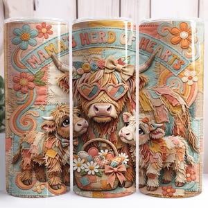 May include: A tumbler featuring a whimsical design with a Highland cow family. The central cow wears heart-shaped sunglasses, surrounded by two calves and a basket of flowers. The text "Mama's Herd of Hearts" is displayed.