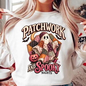 May include: A white long-sleeve sweatshirt featuring a graphic print of a ghost made of colorful patchwork fabric. The design includes a jack-o'-lantern, a spool of thread, bats, and a crescent moon, with the text PATCHWORK AND SPOOKY NIGHTS.