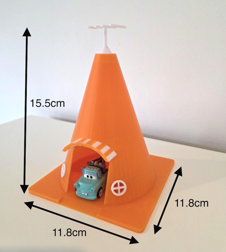 May include: An orange plastic toy traffic cone, 15.5cm tall and 11.8cm wide, with a small blue toy car inside. The cone has a white top and a small arched entrance. The base has two white circular designs.