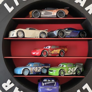 May include: A black circular shelf with the word "LIGHTYEAR" in white letters. The shelf displays toy race cars in various colours, including red, blue, and green. The cars are arranged on red shelves.