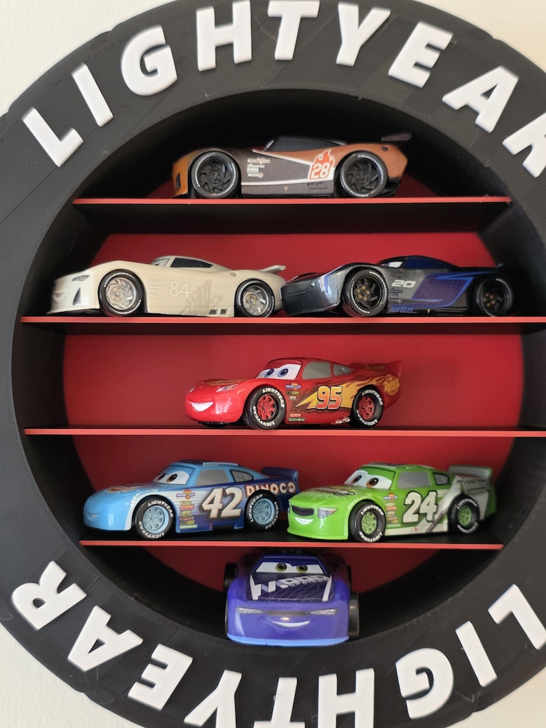 May include: A black circular shelf with the word "LIGHTYEAR" in white letters. The shelf displays toy race cars in various colours, including red, blue, and green. The cars are arranged on red shelves.