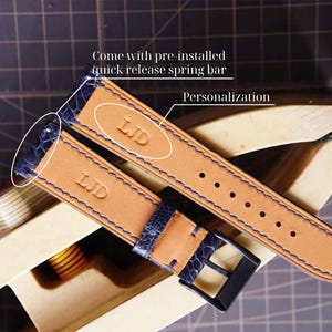 May include: Two leather watch straps with blue accents and stitching, featuring the initials "LJD" embossed on the tan leather. The straps have a blue textured section and a black buckle. The text "Come with pre-installed quick release spring bar" and "Personalization" are visible.