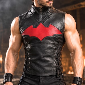 May include: A black sleeveless leather vest featuring a high collar with a front zip closure and a prominent red bat-shaped emblem on the chest. The sides of the vest are detailed with black lace-up cord adjustments and metal eyelets.