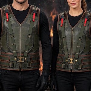 May include: A dark olive green tactical vest featuring a central zip closure, vertical olive webbing straps with brass-toned eyelets, and red accents on the shoulder buckles. The vest includes a horizontal waist belt with a central brass buckle.