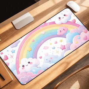 May include: A rectangular desk mat featuring a pastel-colored illustration of a rainbow, smiling clouds, small pink hearts, and yellow stars against a white background. The design includes soft shades of pink, blue, yellow, and purple throughout.