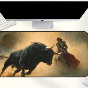 May include: A rectangular mousepad featuring a painting of a bullfight. A black bull with large horns charges towards a matador in a red cape. The background is a hazy, sepia-toned arena.