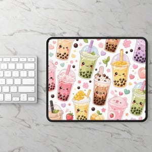 May include: A rectangular mouse pad featuring a repeating pattern of various colorful bubble tea drinks with cute smiling faces, boba pearls, and small hearts on a white background. The drinks include green, pink, brown, and yellow variations.