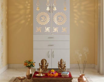 Op de afbeelding: Een witte houten gebedsmeubel met ingewikkelde uitgesneden ontwerpen, met het Om-symbool en andere religieuze motieven. De kast is versierd met twee deuren en lades. Een kleine tafel ervoor toont religieuze beelden, bloemen en wierook.