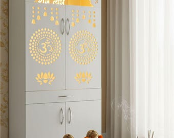 Op de afbeelding: Een witte kast met ingewikkelde uitgesneden ontwerpen en de tekst "राम लाभ". De kast heeft een decoratieve bovenkant, deuren en een lade. Twee gouden beelden van Ganesha staan op een kleine houten tafel voor de kast, versierd met oranje bloemenslingers.