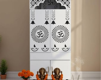 Op de afbeelding: Een witte houten kast met ingewikkelde zwarte uitgesneden ontwerpen, waaronder het Om-symbool en een Swastika. Twee bronzen beelden van een godheid staan op een houten platform, versierd met bloemenslingers. Wierook en oranje bloemen in een vaas zijn ook aanwezig.