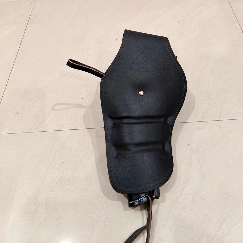 Peut inclure: Un &eacute;tui en cuir noir avec un design incurv&eacute;, dot&eacute; d'une fermeture &agrave; bouton-pression et d'une boucle pour une ceinture. L'&eacute;tui a une couture cousue et une attache en cuir en bas.