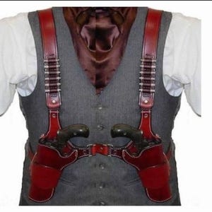 Könnte beinhalten: Ein rotes Leder-Doppelholster mit passendem Gürtel und Schultergurten. Das Holster ist für zwei Revolver konzipiert. Die Riemen haben dekorative Metallnieten. Die Person trägt eine graue Weste und ein weißes Hemd.