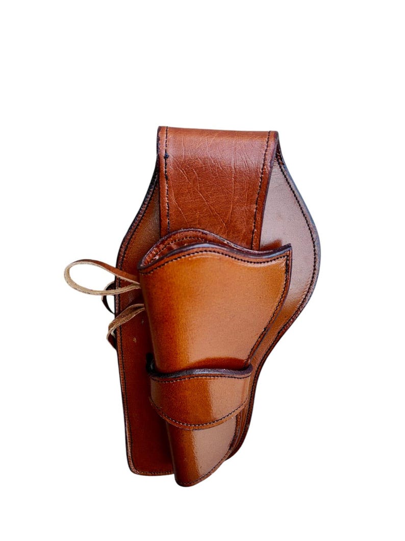 May include: A brown leather holster with a glossy finish. The holster has a curved design with a flap and a loop for securing. The leather is a rich, warm brown color, and the stitching is visible.