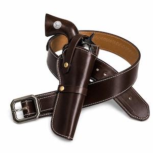 Peut inclure: Un étui en cuir marron foncé contenant un revolver avec une poignée en bois sombre ornée d'une incrustation argentée. L'étui est fixé à une ceinture en cuir marron assortie avec des coutures blanches et une boucle métallique enroulée.