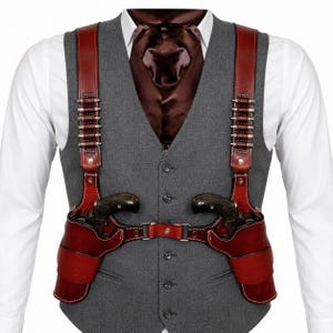 Peut inclure: Un harnais d'épaule double en cuir rouge foncé avec des boucles de cartouches intégrées sur chaque sangle, porté sur un gilet gris boutonné, une chemise blanche à col et une cravate en satin marron foncé. Le système contient deux revolvers noirs.