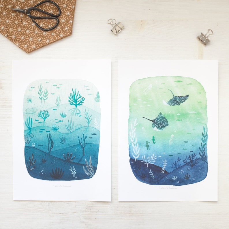 May include: Two watercolor illustrations of underwater scenes. The first shows a variety of sea life, including coral, seaweed, and fish, in shades of blue and green. The second shows two stingrays swimming in a green and blue ocean.