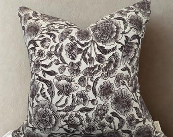 May include: Square throw pillow with a floral pattern in shades of brown and white. The pillow features a detailed botanical design of flowers and leaves, creating a classic and elegant aesthetic. The pillow is likely made of a soft fabric.
