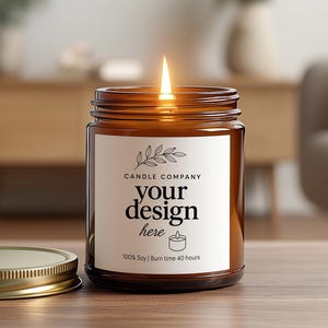 May include: An amber glass candle jar with a gold lid is on a wooden surface, with a lit flame. The candle has a white label with the text "CANDLE COMPANY" and "your design here". The candle is labeled "100% Soy | Burn time 40 hours".