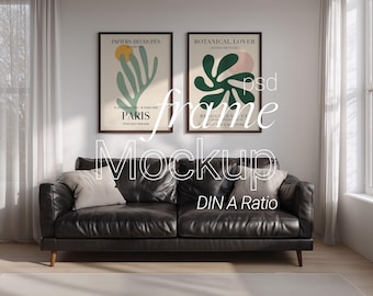May include: A living room scene featuring a black leather sofa with two throw pillows, beneath two framed art prints. The prints have a beige background with abstract shapes in green, pink, and yellow. The text on the prints reads "PAPIERS DÉCOUPÉS PARIS" and "BOTANICAL LOVER".