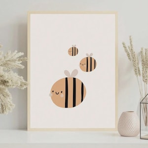 May include: A framed art print featuring three cartoon bees. The bees are tan with black stripes and small gray wings. The largest bee has a smiling face. The background is a light beige color.