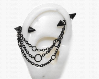 Peut inclure: Bijou d'oreille industriel noir avec trois clous pointus et plusieurs chaînes pendantes. Le bijou d'oreille est conçu pour être porté sur l'oreille et est en métal noir. Les chaînes relient les clous, créant un look unique et audacieux.