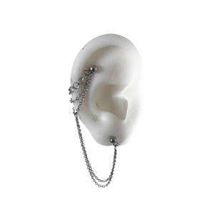 May include: A silver chain earring with a barbell and chain design. The earring is attached to a white ear model. The chain dangles from the top of the ear to the bottom, with a small ball at each end.