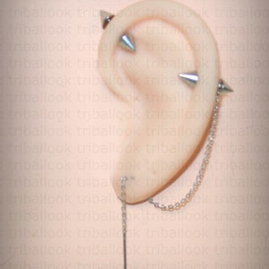 May include: A silver ear cuff with a chain connecting to a long, thin silver spike. The ear cuff has two silver spikes on the top.