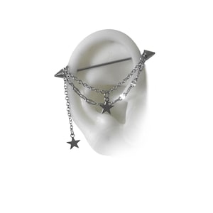 May include: Silver industrial barbell earring with dangling star charms. The barbell features a chain design with multiple star pendants. The earring is shown on a white ear model, showcasing the jewelry's design and details.