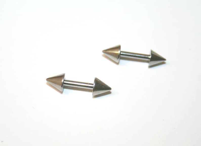 May include: Two silver barbell style body piercing jewellery pieces with pointed ends.