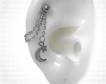 May include: A silver chain earring with a crescent moon and star charm. The earring is attached to a silver ball stud.