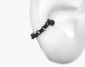 May include: Black chain ear cuff with a small black bead at the end. The cuff is worn on a white mannequin ear.