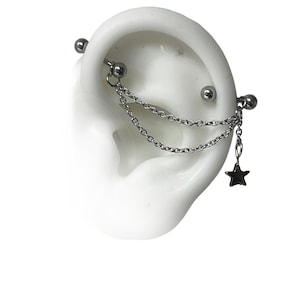 以下が含まれることがあります： 2本のチェーンと星形のチャームが付いたシルバーのイヤーカフ。カフはサージカルステンレス製で、耳の上部に着用するように設計されています。