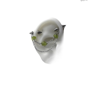 Industrial piercing jewelry with peridot stones and chains. spike ends