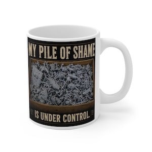 Puede incluir: Una taza de cerámica blanca con un gráfico de una caja de madera llena de figuras en miniatura grises sin pintar. El texto MY PILE OF SHAME en la parte superior e IS UNDER CONTROL en la parte inferior aparece en una fuente serif beige desgastada sobre un fondo negro.