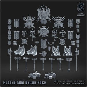 May include: A collection of grey miniature gaming accessories including shields, banners, capes, hammers, axes, and firearms. The set features various heraldic emblems, crests, and weapon designs. Text reads PLATED ARM DECOR PACK and HYDRA WORKSHOP.