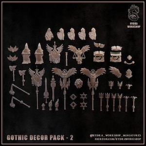 Puede incluir: Una colección de accesorios de juego en miniatura de resina que incluye estatuas aladas, escudos, hachas, mazas, libros y estandartes. El conjunto está etiquetado como GOTHIC DECOR PACK - 2 y presenta el logotipo de Hydra Workshop con varios objetos de fantasía detallados.