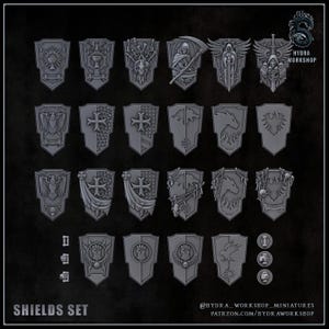 May include: A collection of twenty-three grey miniature shields featuring various embossed designs including skulls, eagles, crosses, and dragons. The set includes small circular and rectangular components, with the text HYDRA WORKSHOP visible.