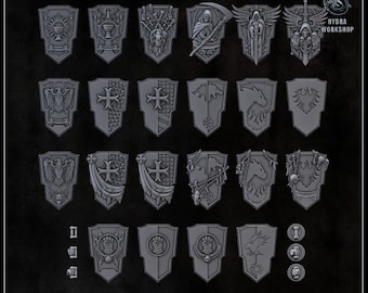 May include: A collection of twenty-three grey miniature shields featuring various embossed designs including skulls, eagles, crosses, and dragons. The set includes small circular and rectangular components, with the text HYDRA WORKSHOP visible.