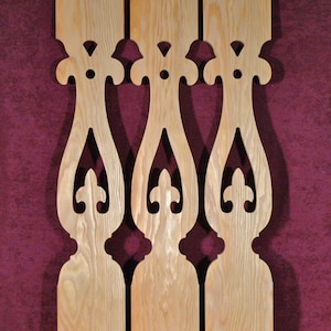 May include: Three wooden decorative panels with a light wood grain. Each panel features a repeating ornate cutout design with curved lines and symmetrical shapes. The panels are displayed against a dark red background.