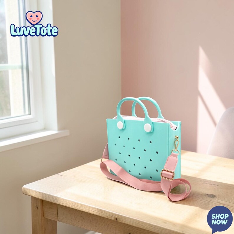 May include: A light blue tote bag with a pink shoulder strap and handles. The bag has a perforated design and white accents. The bag is sitting on a wooden table. The logo "Luvetote" is visible in the upper left corner.