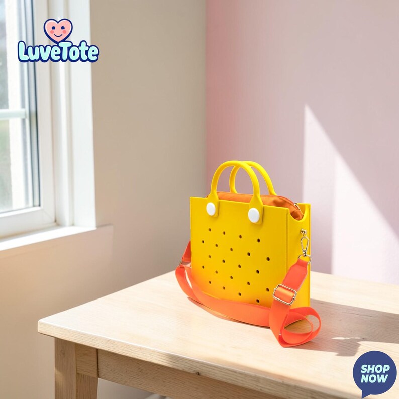 May include: A yellow tote bag with a perforated design and orange strap. The bag has white handle attachments and a zipper closure. The bag is sitting on a wooden table. The bag has the text "Luvetote" on the top left.
