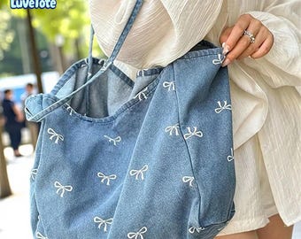 May include: A blue denim tote bag with white bow patterns. The bag has a shoulder strap and a large capacity. The bag is made of a soft denim material and is suitable for everyday use.