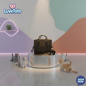 May include: A black tote bag with a perforated design and a shoulder strap sits on a silver pedestal. The bag has two handles and is surrounded by small cat figurines. The Luvetote logo is visible in the upper left corner, and the words "SHOP NOW" are in the lower right corner.