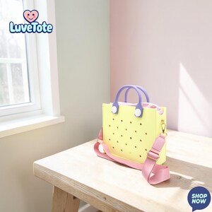 May include: A yellow tote bag with a perforated design, purple handles, and a pink shoulder strap. The bag has a zipper closure and gold-colored hardware. The brand name "Luvetote" is visible in the upper left corner.
